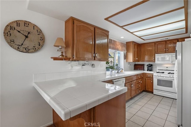 kitchen featuring kitchen peninsula, sink, white appliances, tile counters, and light tile patterned floors