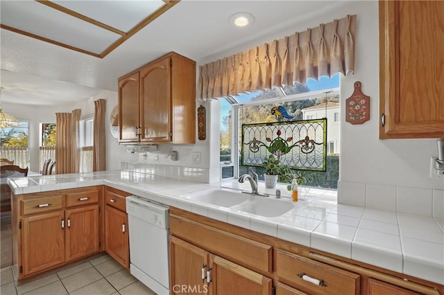 kitchen featuring white dishwasher, sink, plenty of natural light, and tile countertops