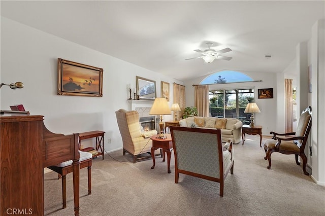 carpeted living room featuring ceiling fan, a tiled fireplace, and lofted ceiling