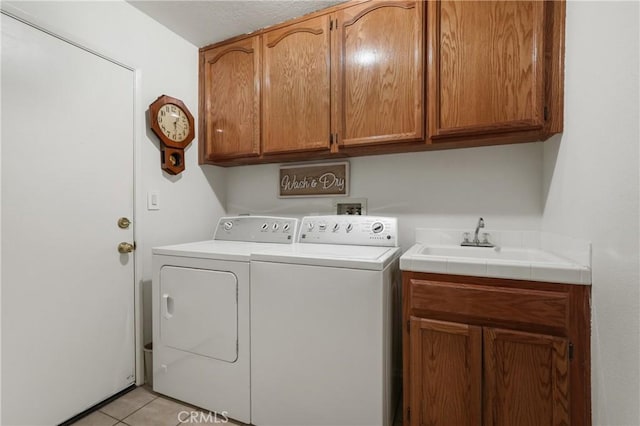 laundry room with washer and clothes dryer, light tile patterned flooring, sink, and cabinets