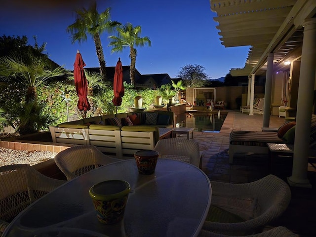 patio terrace at dusk with an outdoor hangout area and a swimming pool