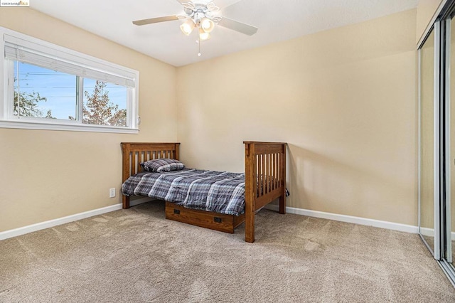 carpeted bedroom featuring ceiling fan and a closet