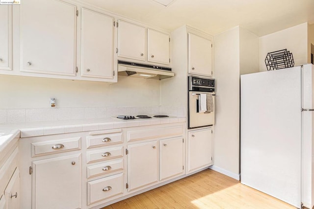 kitchen featuring tile counters, light hardwood / wood-style flooring, white cabinetry, and white appliances