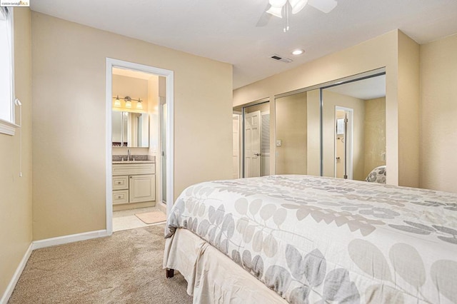 carpeted bedroom with ceiling fan, sink, and ensuite bath