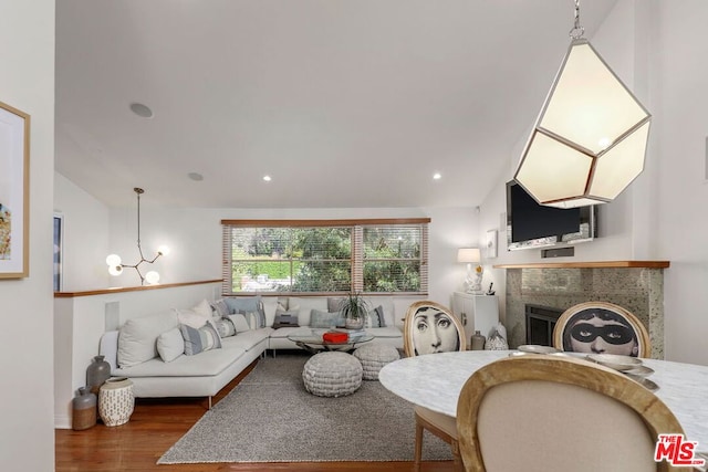 living room featuring hardwood / wood-style flooring, an inviting chandelier, and vaulted ceiling