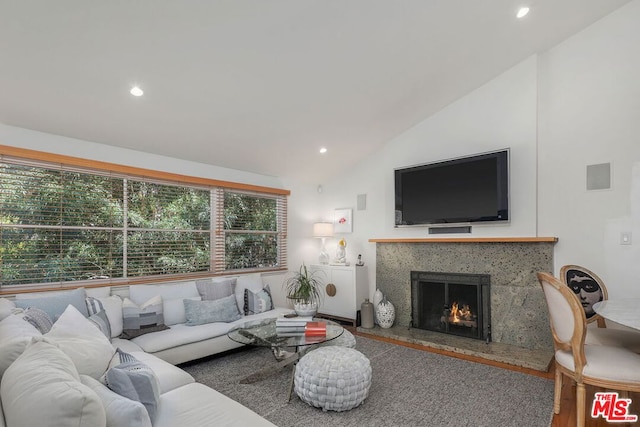 living room with a high end fireplace, hardwood / wood-style flooring, and lofted ceiling