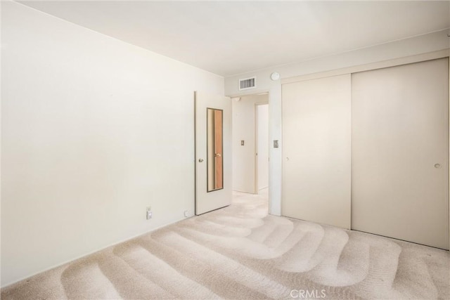 unfurnished bedroom with light colored carpet and a closet