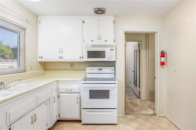 kitchen with sink, white appliances, light colored carpet, and white cabinets