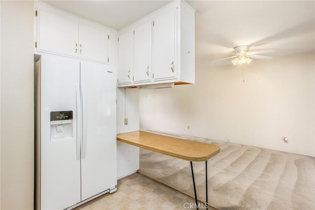 kitchen with white cabinetry, white refrigerator with ice dispenser, and ceiling fan