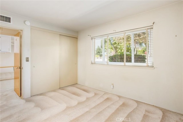 unfurnished bedroom featuring light colored carpet and a closet