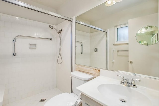 bathroom with tiled shower, vanity, and toilet