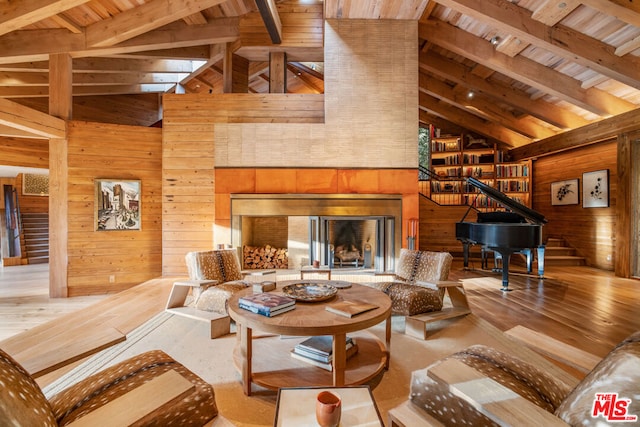 living room with light wood-type flooring, wooden walls, beam ceiling, high vaulted ceiling, and wooden ceiling