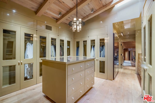 walk in closet featuring a notable chandelier, lofted ceiling with beams, light hardwood / wood-style floors, and french doors