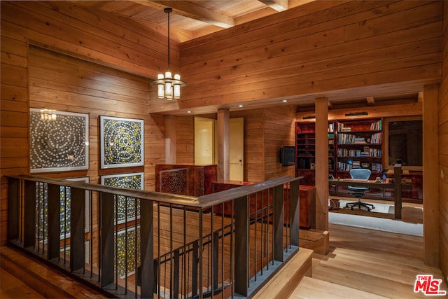 hall with wood walls, wooden ceiling, hardwood / wood-style flooring, a notable chandelier, and beam ceiling