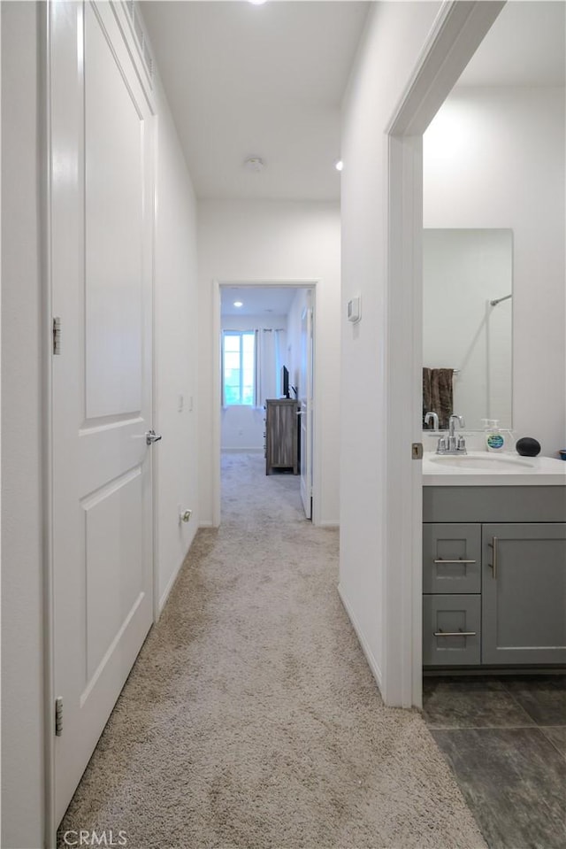 hallway featuring dark carpet and sink