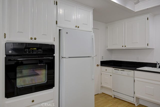 kitchen with white cabinetry, white appliances, sink, and light hardwood / wood-style flooring