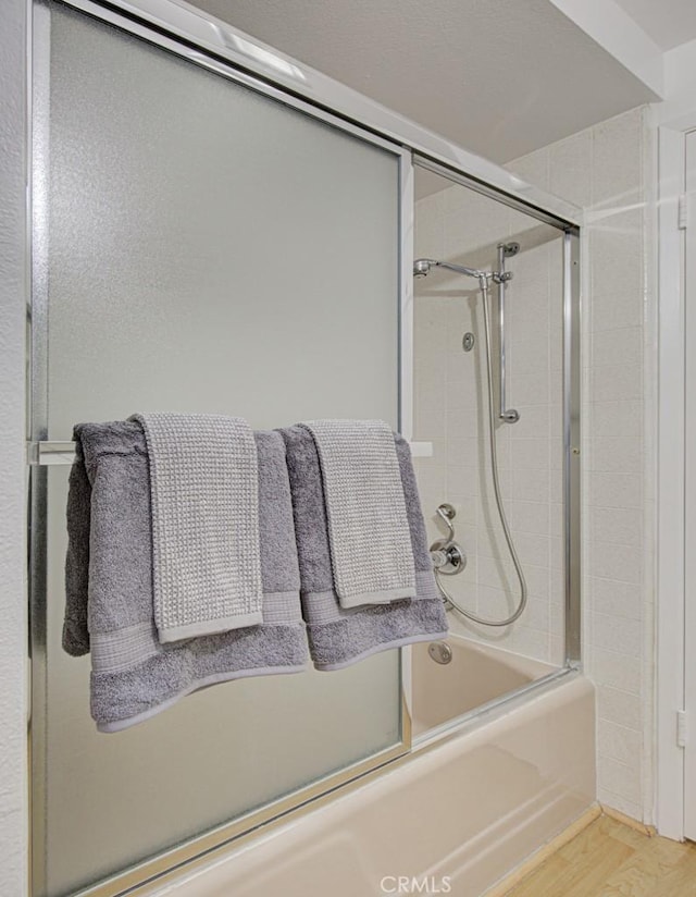 bathroom with shower / bath combination with glass door and hardwood / wood-style floors