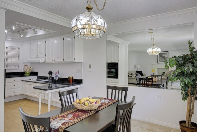 dining area with track lighting, a textured ceiling, crown molding, light hardwood / wood-style flooring, and a chandelier