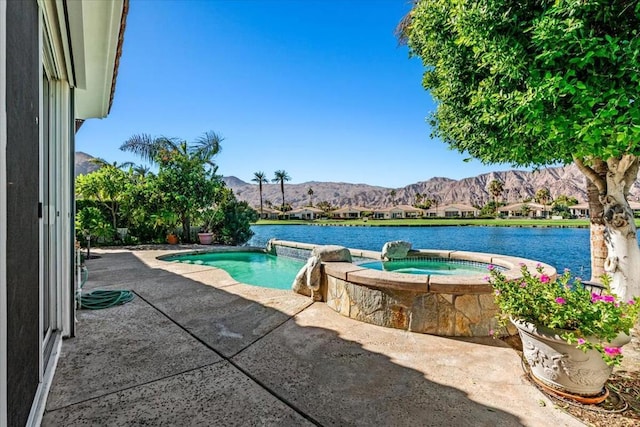 view of swimming pool with an in ground hot tub, a patio, pool water feature, and a water and mountain view