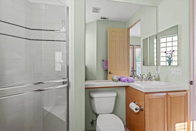 bathroom with a shower with door, vanity, and toilet