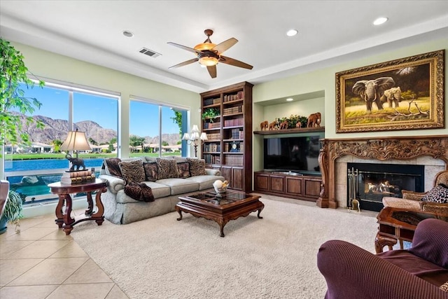 living room featuring ceiling fan, light tile patterned flooring, and a high end fireplace