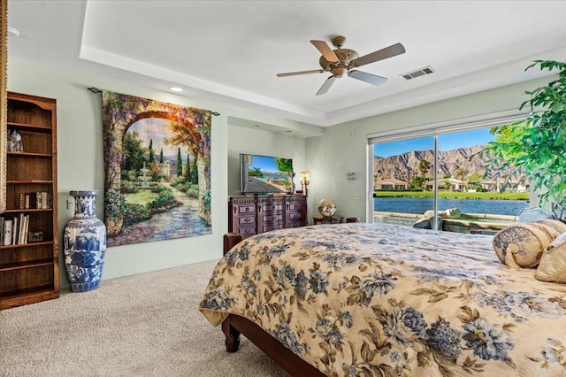 bedroom with access to outside, a raised ceiling, ceiling fan, and carpet