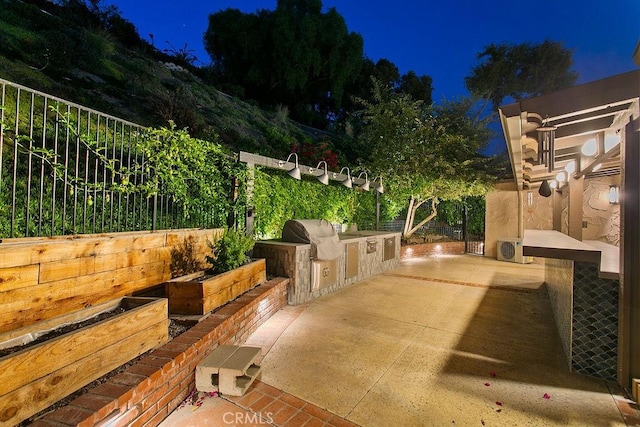 patio at twilight with ac unit, a grill, and exterior kitchen