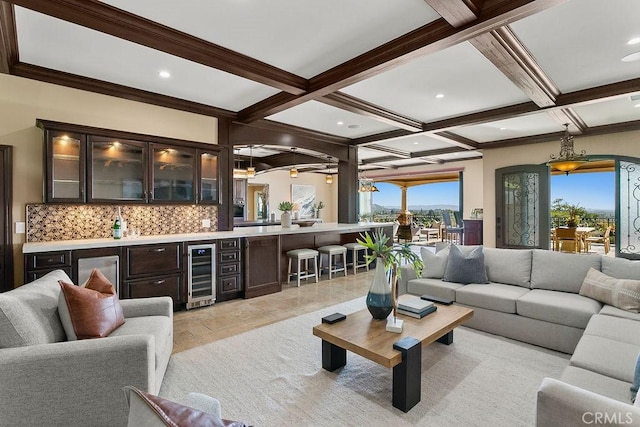 living room featuring coffered ceiling, ceiling fan, bar, beam ceiling, and beverage cooler