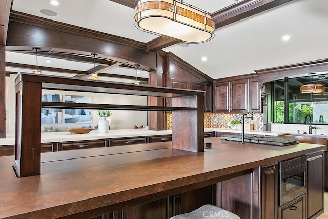 kitchen featuring dark brown cabinetry, tasteful backsplash, stainless steel microwave, and crown molding