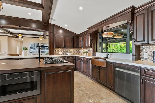 kitchen with appliances with stainless steel finishes, dark brown cabinetry, sink, beam ceiling, and pendant lighting