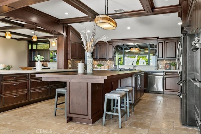 kitchen with a kitchen breakfast bar, decorative backsplash, beamed ceiling, and stainless steel appliances