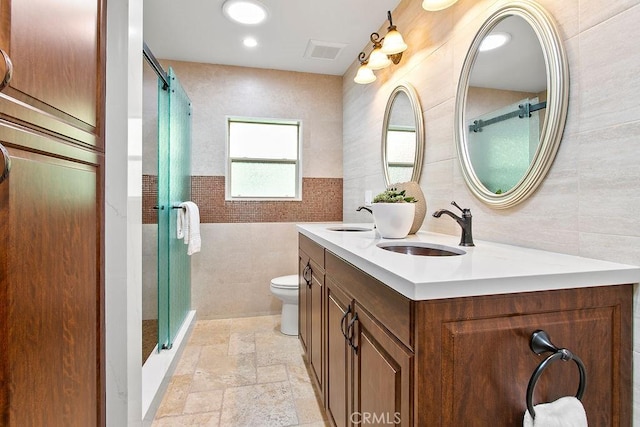 bathroom with walk in shower, vanity, tile walls, and toilet