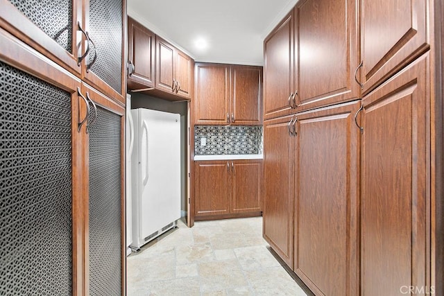 kitchen with white refrigerator, ornamental molding, and backsplash