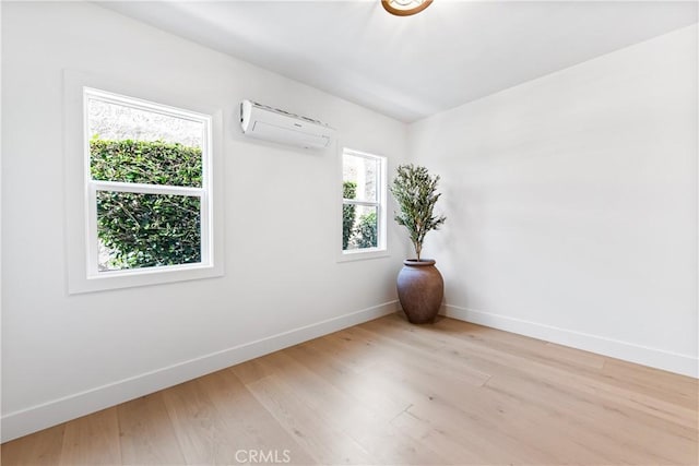 unfurnished room with a wall mounted AC, plenty of natural light, and light hardwood / wood-style floors