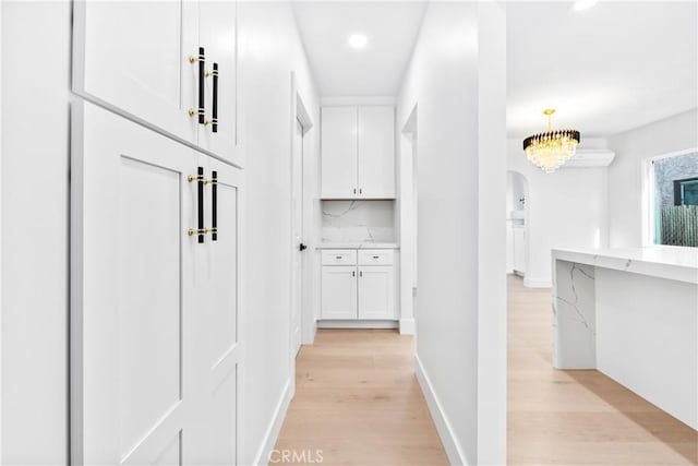 hallway with light hardwood / wood-style floors and a notable chandelier