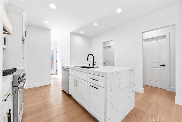 kitchen featuring stainless steel appliances, sink, a center island with sink, light hardwood / wood-style flooring, and white cabinets