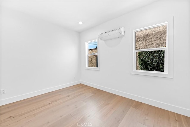 unfurnished room featuring an AC wall unit and light hardwood / wood-style floors