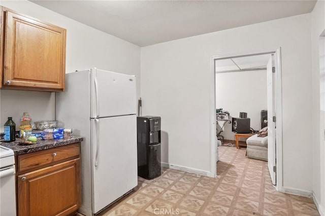 kitchen with white fridge and dark stone countertops