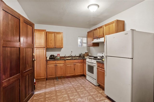 kitchen featuring sink, dark stone counters, and white appliances