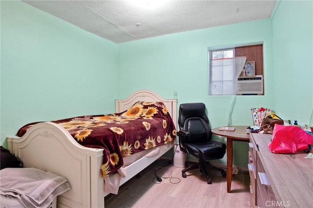 bedroom with cooling unit and light hardwood / wood-style floors