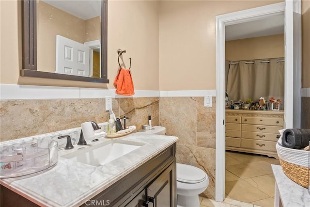 bathroom with tile patterned flooring, vanity, toilet, and tile walls