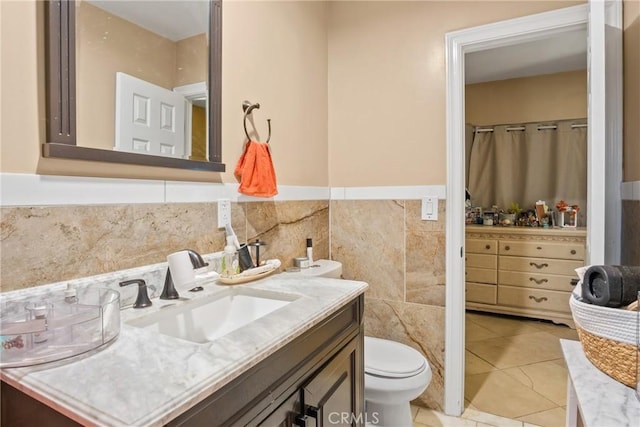 bathroom with toilet, tile patterned flooring, tile walls, and vanity