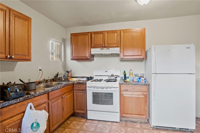 kitchen featuring sink, white appliances, and dark stone counters