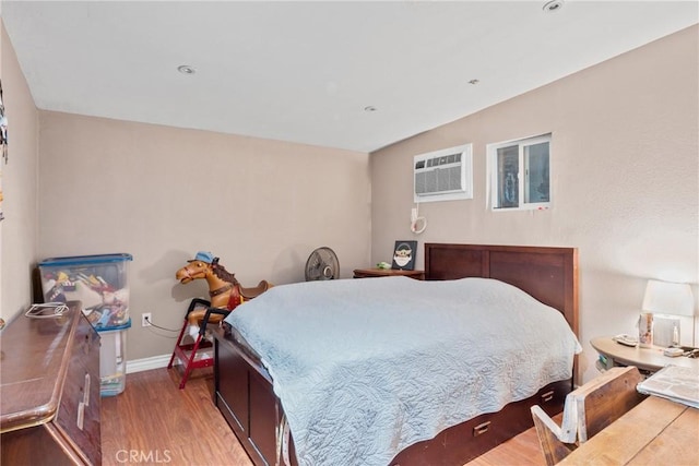 bedroom with wood-type flooring and a wall unit AC