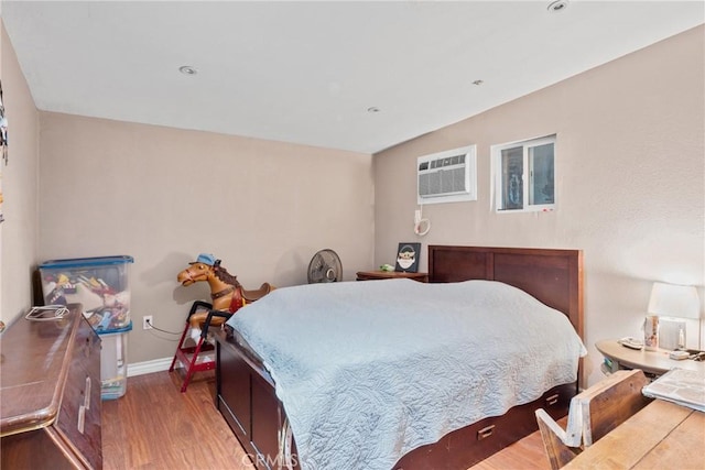 bedroom featuring hardwood / wood-style flooring and a wall mounted air conditioner