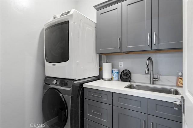 washroom with cabinets, stacked washer / dryer, and sink