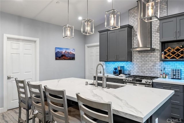 kitchen featuring gray cabinets, a kitchen island with sink, hanging light fixtures, and high end stainless steel range oven