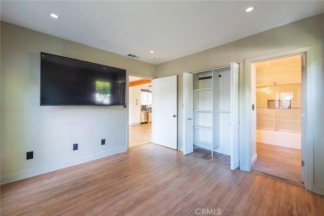 unfurnished bedroom featuring connected bathroom and light hardwood / wood-style flooring