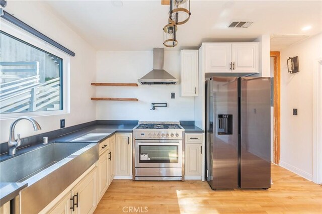 kitchen with wall chimney exhaust hood, light hardwood / wood-style floors, sink, and appliances with stainless steel finishes