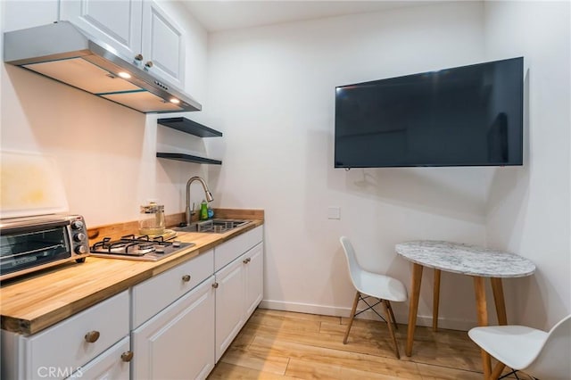 kitchen with white cabinetry, sink, stainless steel gas cooktop, wood counters, and light hardwood / wood-style flooring